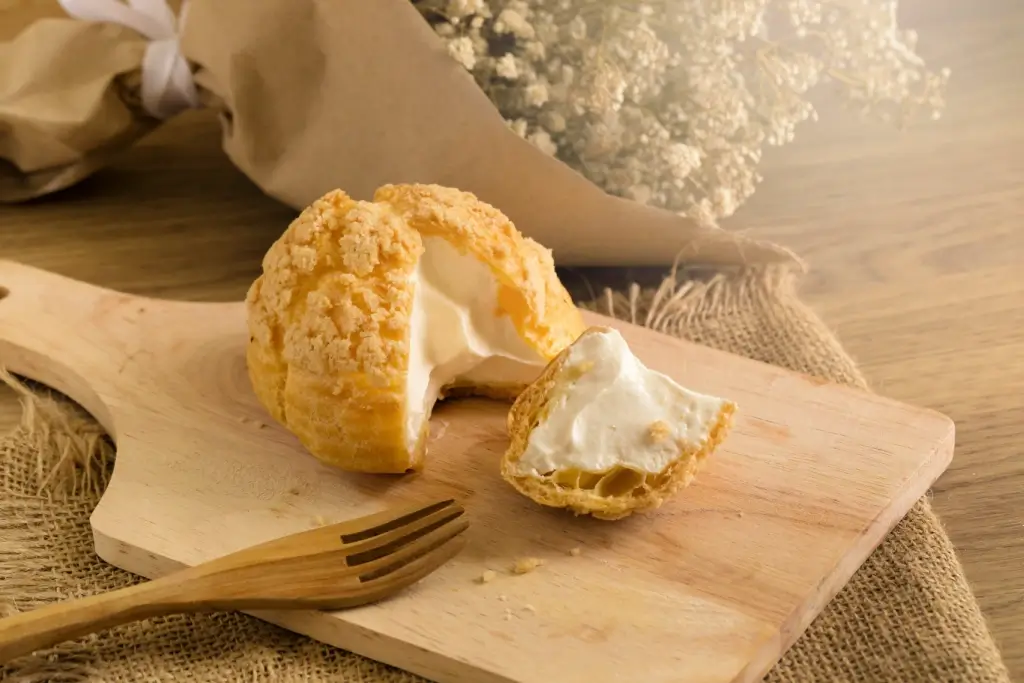 A cutting board with a choux cream on top.