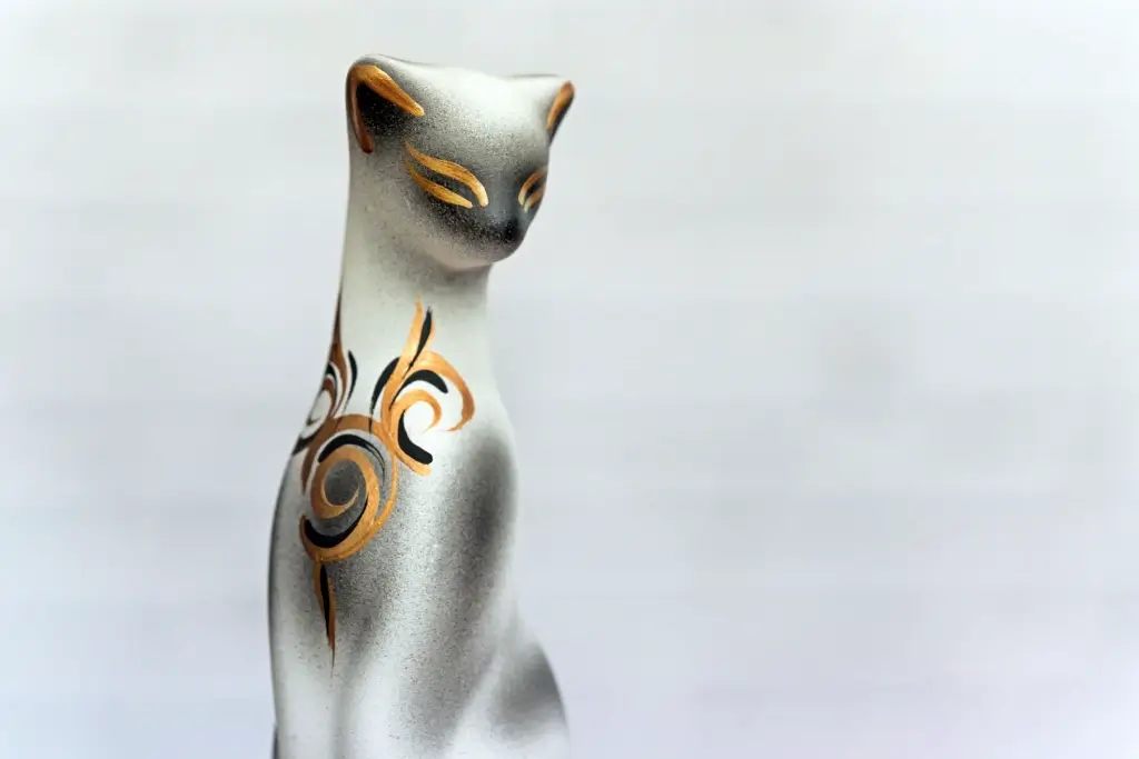 A silver nekomata statue with gold accents.