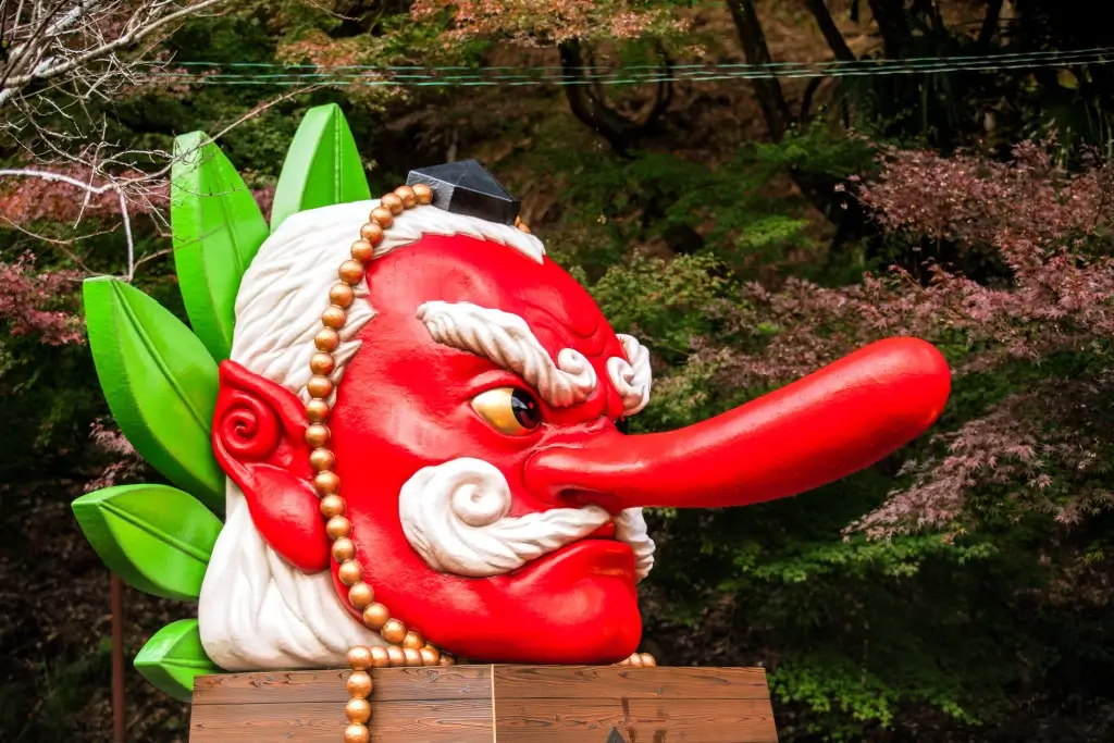 A red tengu head statue with a long red nose.