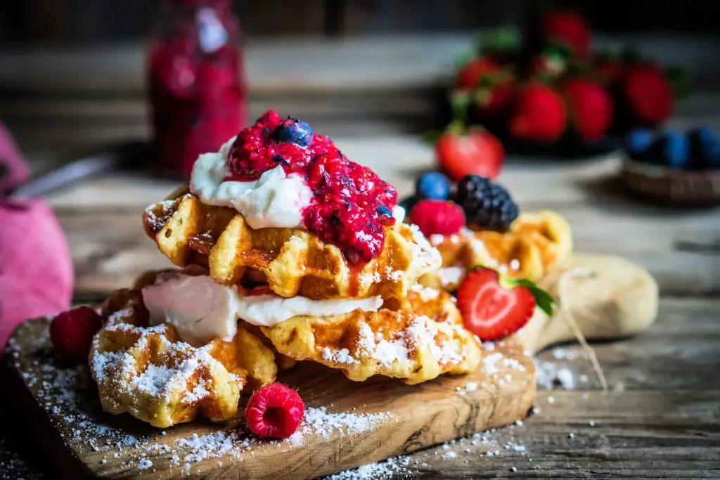 A plate of Belgian waffles with berries on top.