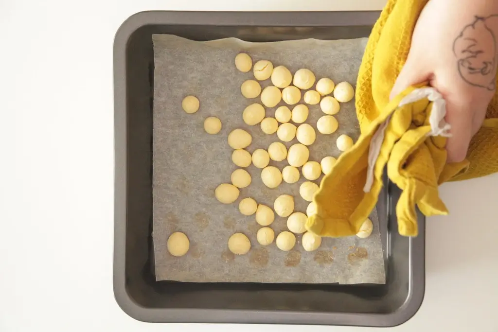 Someone dropping a bunch of tamago "bolo" cookies on a baking pan.