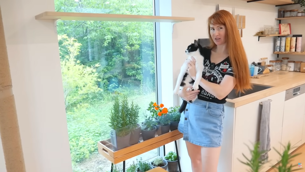 A red-headed woman standing by her DIY Herb Garden Shelf